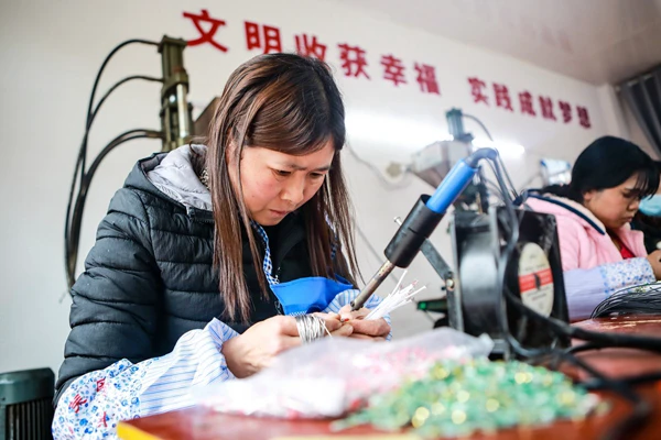 毕节市七星关区柏杨林街道易地扶贫搬迁安置点和美社区搬迁户彭玉洁妻子王敏在扶贫车间里上班 陈曦摄